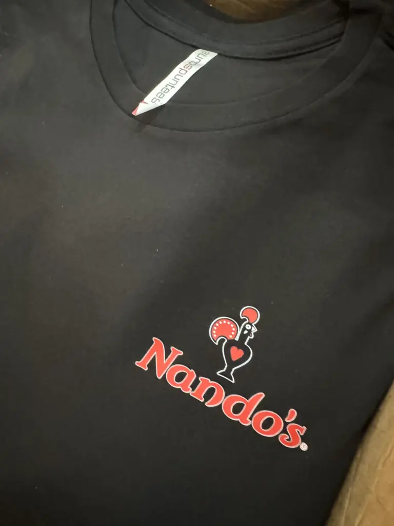 Black staff t-shirt with the red Nando's logo printed on the chest